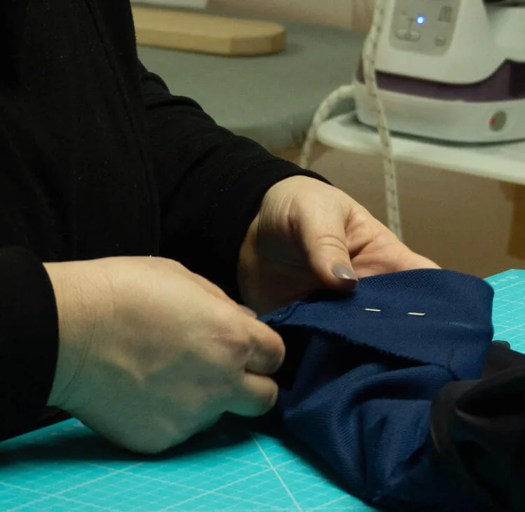 Manos prendiendo con alfileres un arreglo de ropa